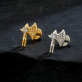 Gold and silver axe-shaped earrings on a dark surface