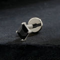 Black square gemstone cufflink on a dark textured background