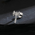 Silver axe-shaped earring on a dark stone surface